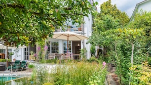 A garden with a pool, outdoor seating, and a building with large windows. - Apartment 'Romantica' with Lake View, Private Terrace and Wi-Fi (Sipplingen)