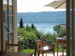 A view from a room with a table and chair, overlooking a body of water and greenery.