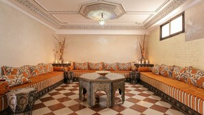 A room with a checkered floor, a central coffee table, and a sofa set with patterned cushions. - Riad Safran – Private Chef, Indoor Pool Gem (Marrakesh)