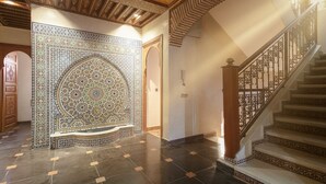 A grand hallway with a large ornate tile wall, a staircase with intricate railings, and a polished floor. - Riad Safran – Private Chef, Indoor Pool Gem (Marrakesh)