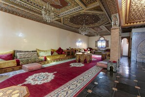 A room with a patterned carpet, a sofa set, a coffee table, and a chandelier.