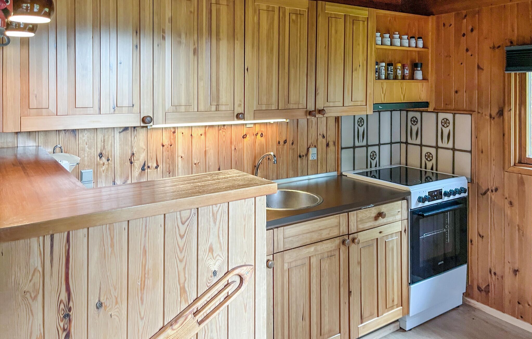 Una cocina con armarios de madera, un lavamanos de acero inoxidable y una estufa blanca.