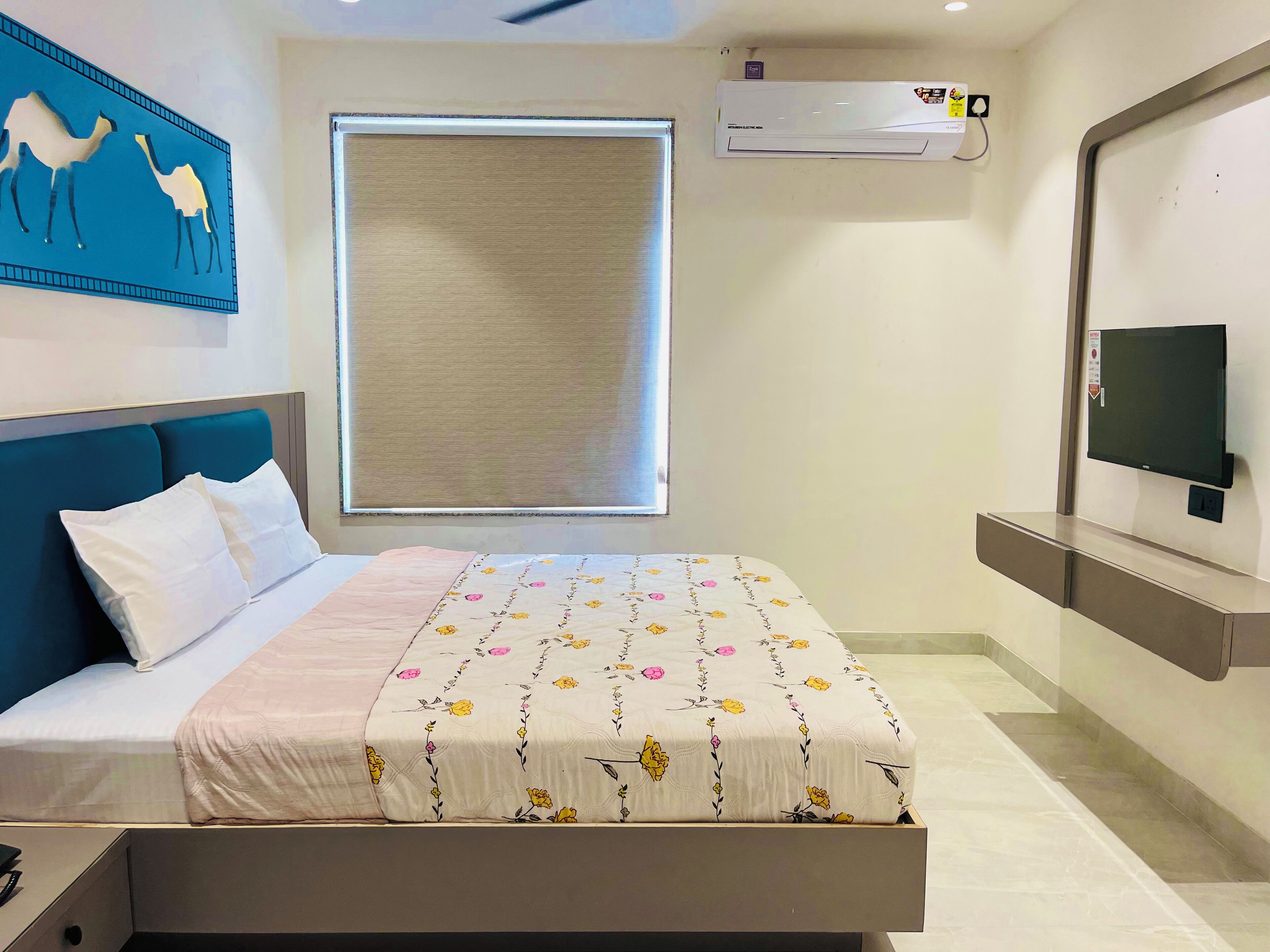 Habitación de hotel moderna con cama, un ventanal con persianas, unidad de aire acondicionado, televisor de pantalla plana y televisor de pared.