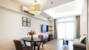 Una sala de estar moderna con comedor, sofá, televisor e iluminación en el techo.