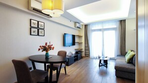 Una sala de estar moderna con comedor, televisor de pantalla plana y un gran ventanal con cortinas.