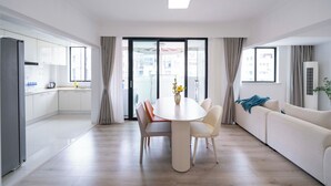 A modern living room with a dining table, sofa, and kitchen area.