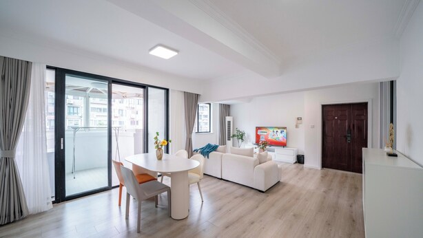 A modern living room with a dining area, a sofa, and a TV.