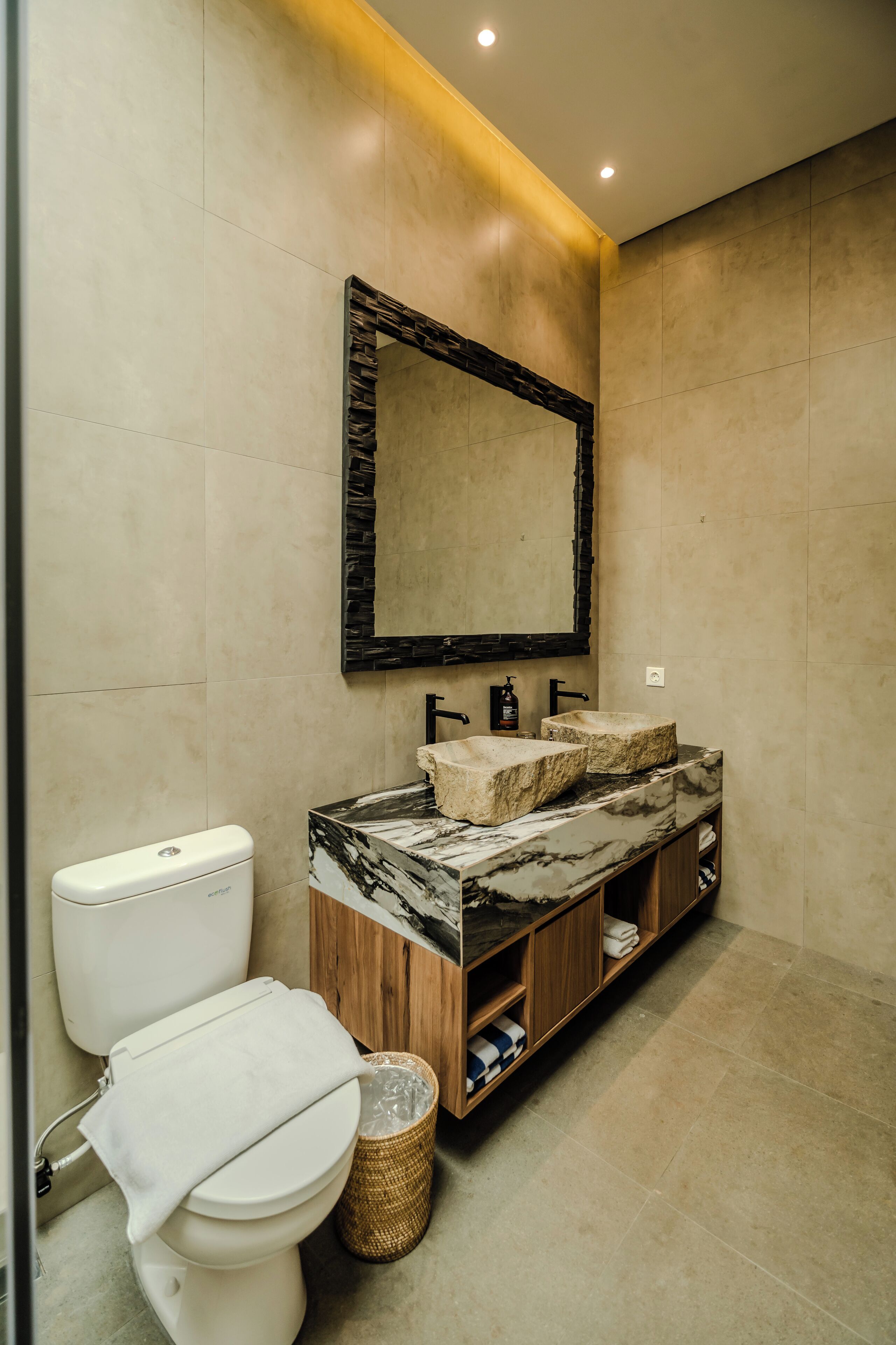 A modern bathroom with a marble sink, wooden vanity, and a large mirror.