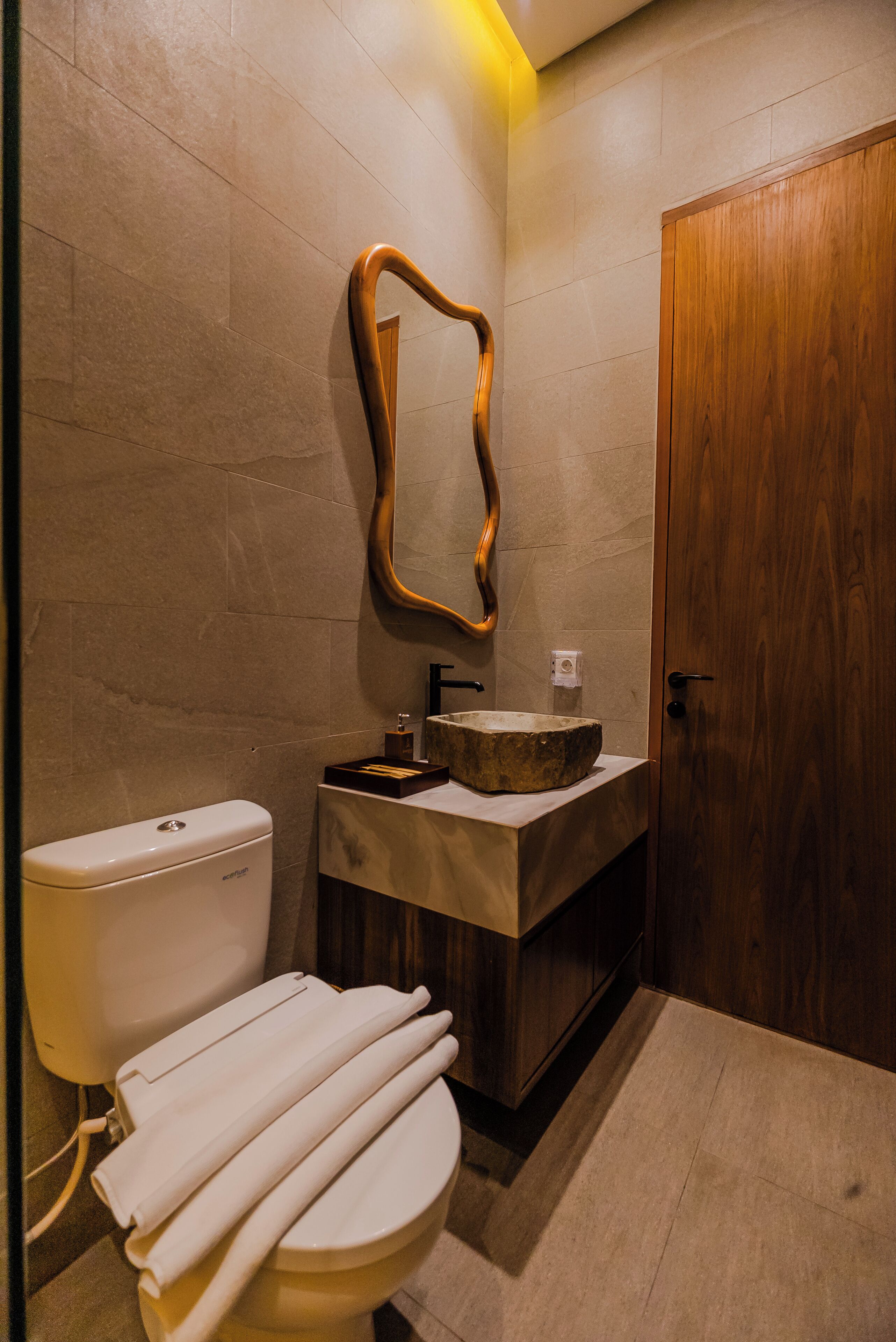 A modern bathroom with a toilet, sink, and wooden door.