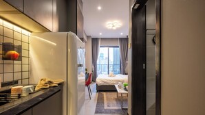 A modern hotel room with a kitchen area, a bed with a view, and a bathroom. - M Residence-Cozy Stay by Soben Homes (Phnom Penh)