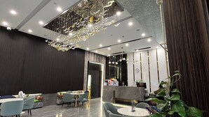 A modern hotel lobby with a reception desk, seating area, and decorative ceiling elements. - M Residence-Cozy Stay by Soben Homes (Phnom Penh)