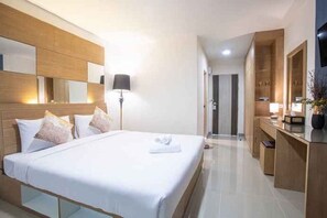 Une chambre d’hôtel avec un grand lit, des lampes de chevet, un miroir et un bureau avec une lampe.