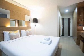 Une chambre d’hôtel avec un grand lit, une lampe de chevet, une armoire et un miroir au mur.