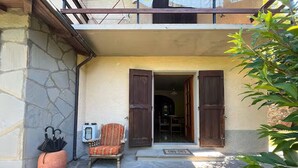 A building entrance with a stone wall, a potted plant, a chair, and a small table. - House with private garden and mountain views (Cutigliano)
