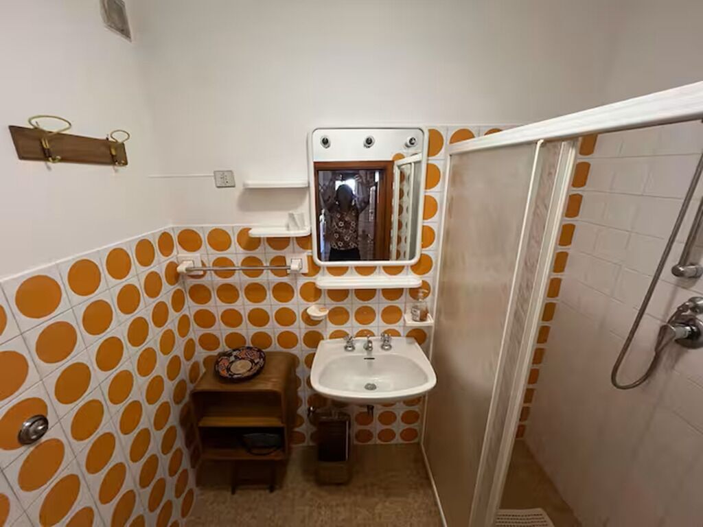 A bathroom with a sink, mirror, and shower.