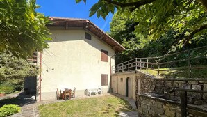 A stone staircase leading to a building with a tiled roof, surrounded by greenery and a clear sky. - House with private garden and mountain views (Cutigliano)