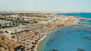 An aerial view of a coastal resort with beach umbrellas, a pool, and a beachfront promenade. - Ali Baba Palace Resort - Families and Couples Only  (Hurghada)