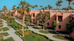 A resort with palm trees, a pathway, and buildings with balconies. - Ali Baba Palace Resort - Families and Couples Only  (Hurghada)