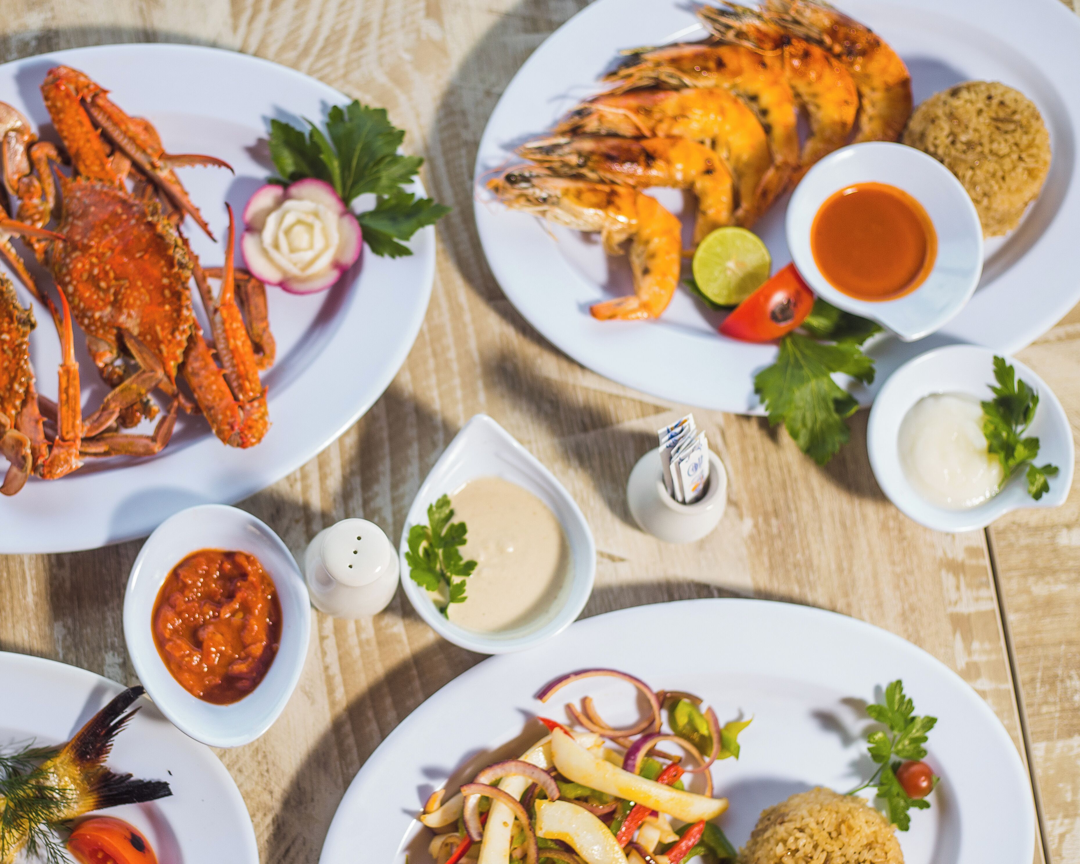 A table with various seafood dishes, including crab legs, shrimp, and a salad with fries.