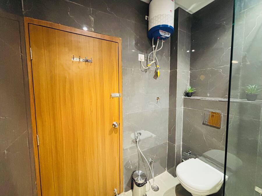 A bathroom with a wooden door, a shower with a glass enclosure, a toilet, and a water heater mounted on the wall.