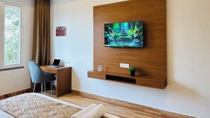 A modern hotel room with a wooden TV stand, a desk, a chair, a bed, and a window with curtains. - Arth Suites Lucknow Gomti Nagar (Lucknow)