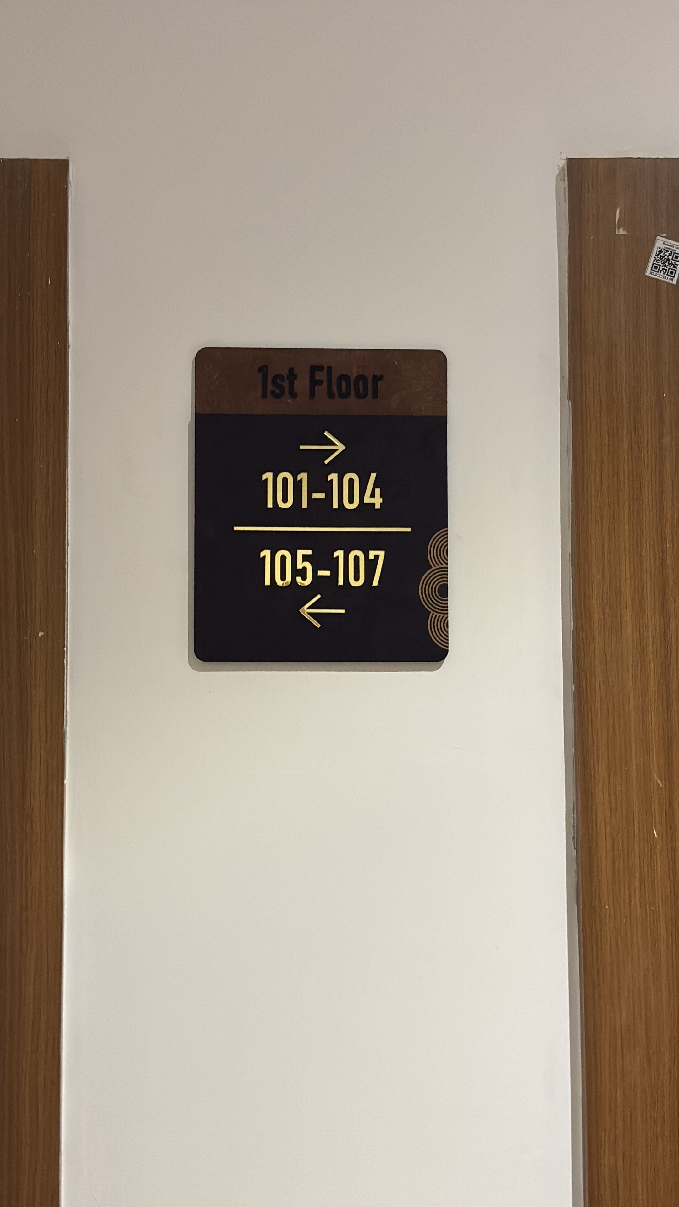 A sign indicating the first floor with room numbers 101-104 and 105-107.