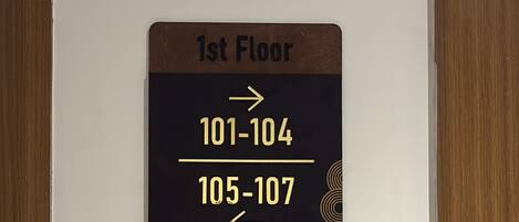A sign indicating the first floor with room numbers 101-104 and 105-107.