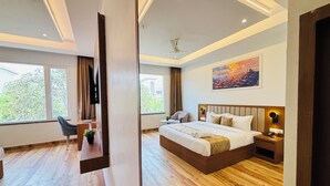 A modern hotel room with a large bed, a desk, a chair, a TV, and a painting on the wall. - Arth Suites Lucknow Gomti Nagar (Lucknow)