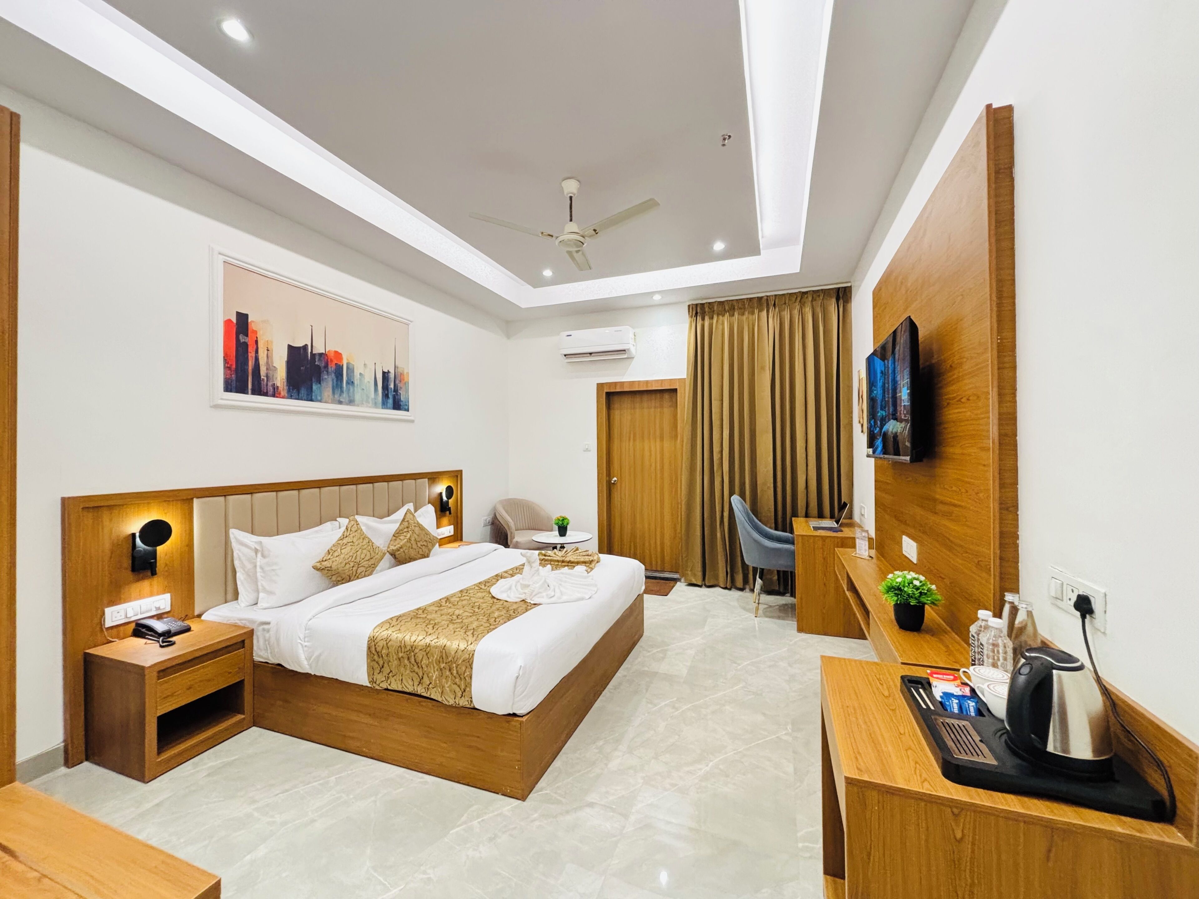 Una habitación de hotel moderna con cama, mesita de noche, escritorio, silla y televisión.