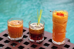 Three glasses of beverages on a wooden table by a pool. - Emana Abian Taksu (Payangan)