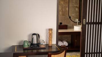 A small wooden table with a kettle, a mug, and a bamboo container.