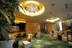 Eine Hotelhalle mit Barbereich, Sitzgelegenheiten und einem Kronleuchter.