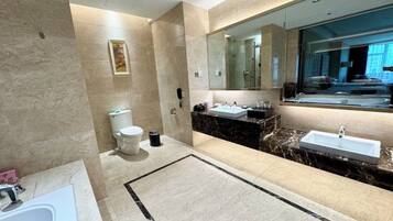 A modern bathroom with a large mirror, a bathtub, a toilet, and a sink.