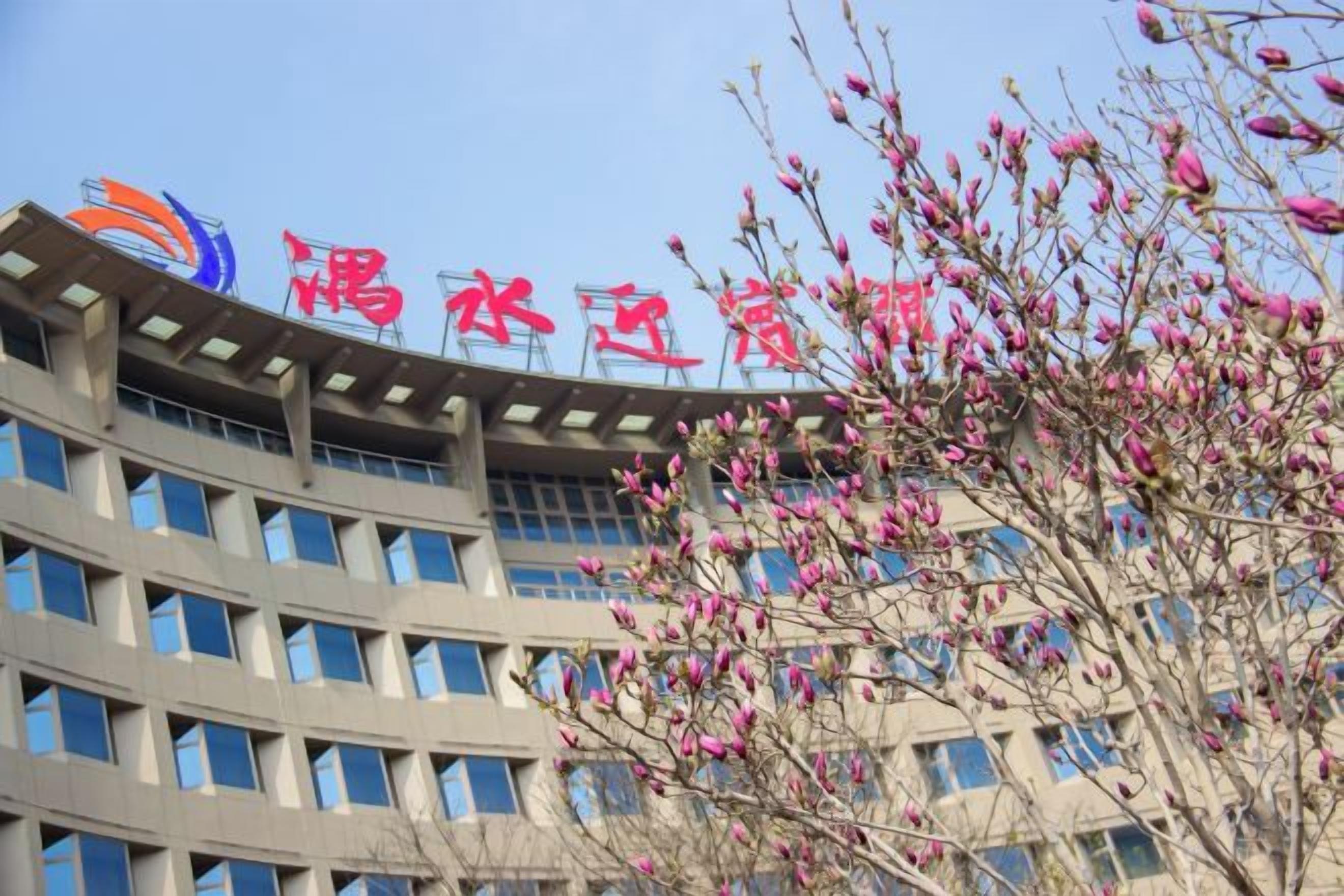 A multi-story building with a curved facade and a logo at the top.