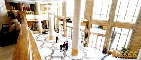 A spacious lobby with high ceilings, large columns, and a grand staircase.