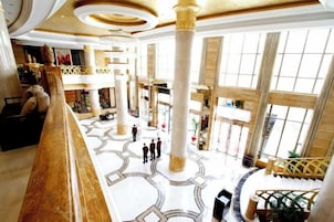 A spacious lobby with high ceilings, large columns, and a grand staircase.