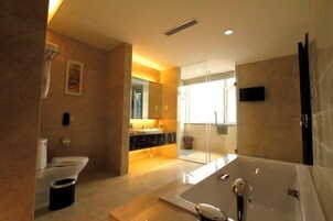 Un baño moderno con una bañera grande, cabina de ducha con mampara de cristal y tocador con espejo.