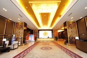 A hotel lobby with a reception desk, a large chandelier, and a patterned carpet. - Yushui Hotel (Shahe)