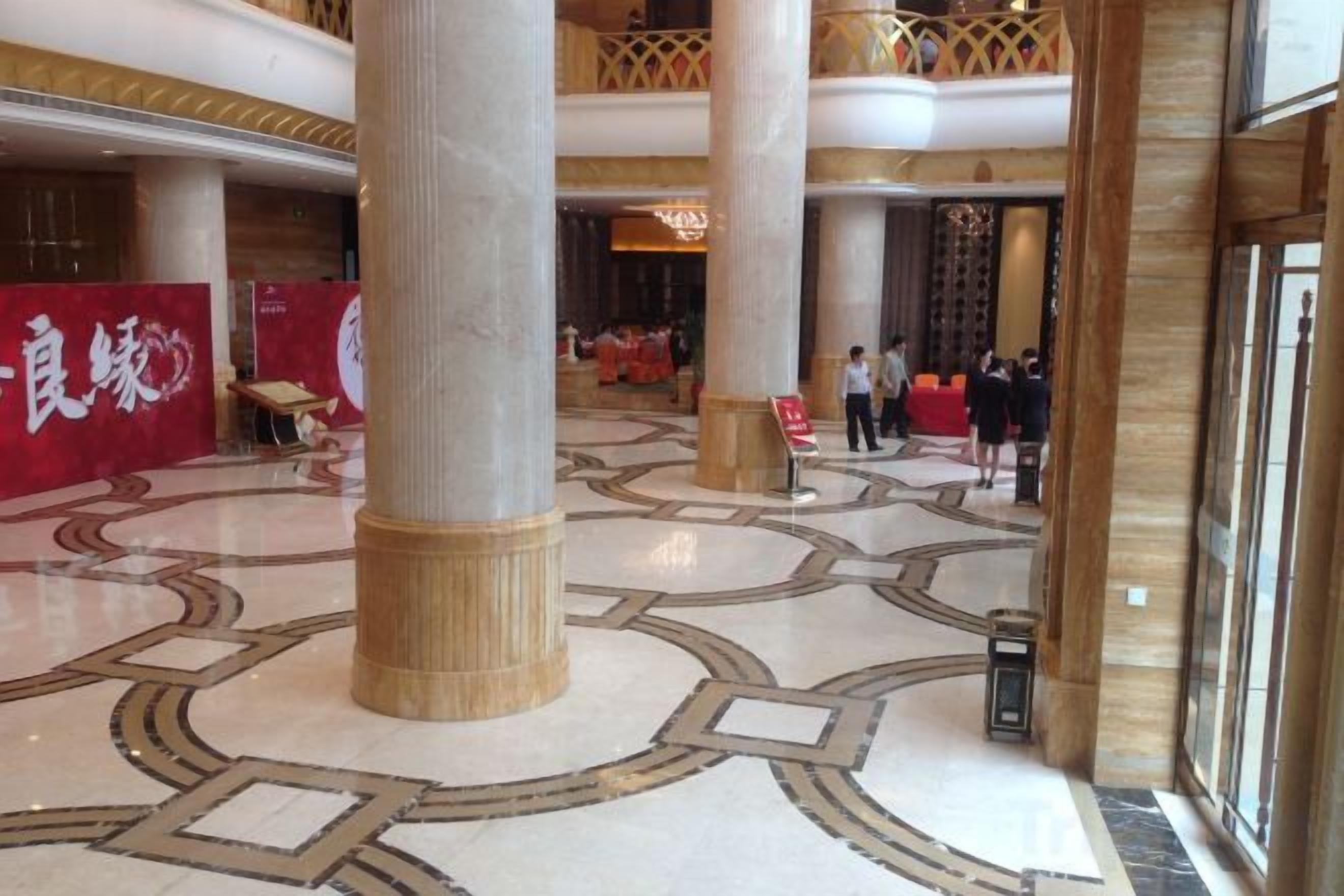 A spacious lobby with a high ceiling, large columns, and a patterned floor.