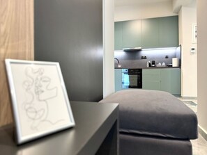 A modern kitchen with a dark countertop, a built-in oven, and a green backsplash. - City Bliss I Trikala Town (Trikala)