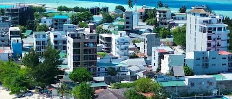 Un hotel frente al mar con varias construcciones, una playa con sombrillas y una vista despejada del océano.