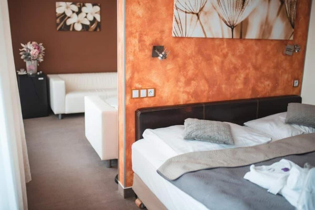 Ein Hotelzimmer mit einem großen Bett, einem weißen Sofa und einer Wand mit Kunstwerken.