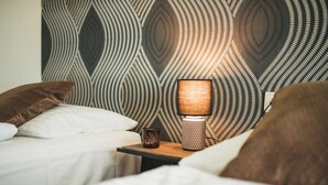 Une chambre à coucher avec un papier peint à motifs, une lampe de chevet et deux oreillers.