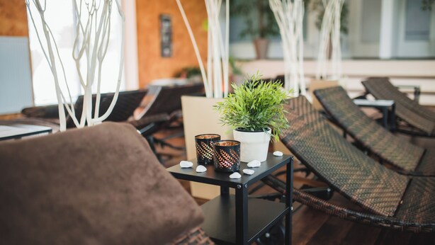 Un espace détente avec des fauteuils inclinables, une petite table agrémentée d’une plante et d’objets décoratifs, et un mur blanc avec une fenêtre en arrière-plan.