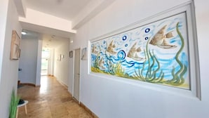 Corredor com uma grande obra de arte emoldurada retratando peixes e algas marinhas.