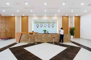A reception area with a reception desk, seating, and a large wall with text. - Victory Hotel Vung Tau - New Wing (Vung Tau)
