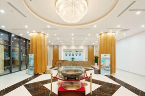 Eine Hotelhalle mit einer Rezeption, einem Chandelier und einem roten Teppich.