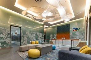 Un hall d’entrée moderne avec des espaces aménagés pour s’asseoir, un comptoir d’accueil et une cloison en verre.