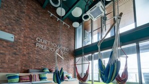 Un studio de yoga avec un mur en briques, une citation inspirante et des hamacs colorés suspendus.