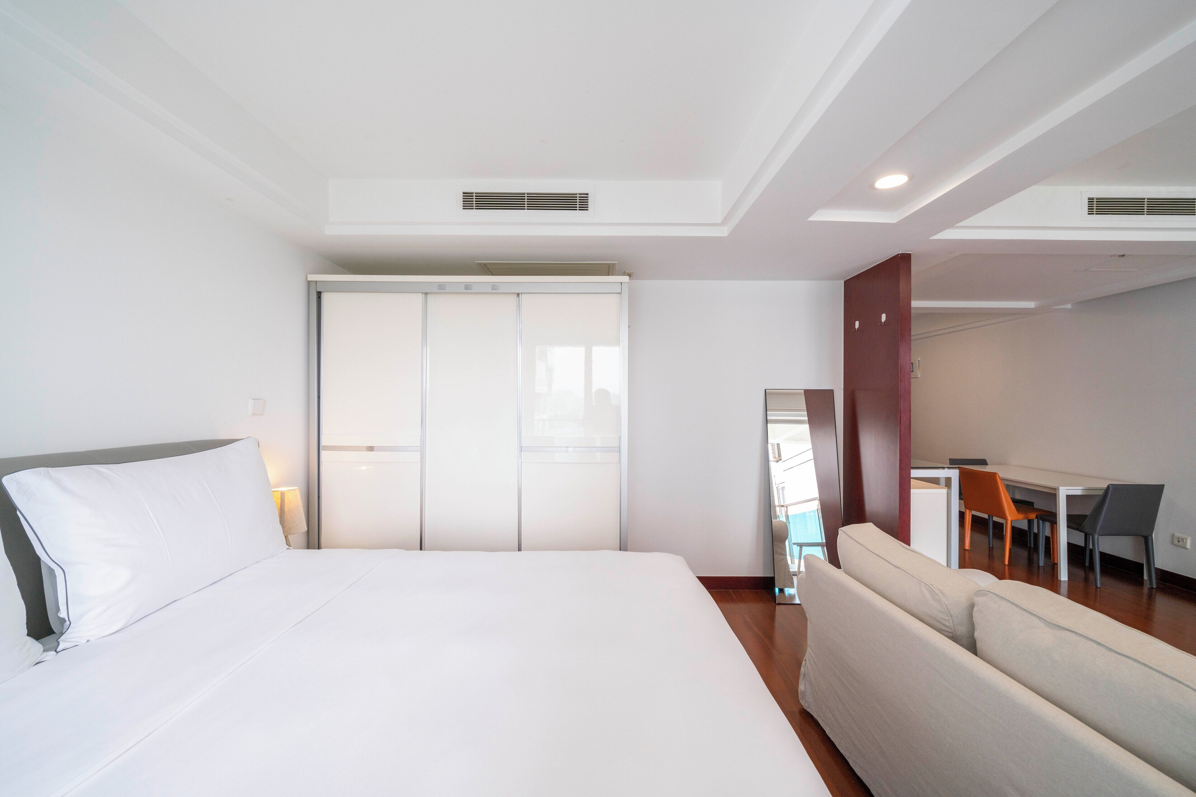 A hotel room with a large bed, a sofa, a desk with chairs, and a sliding door closet.